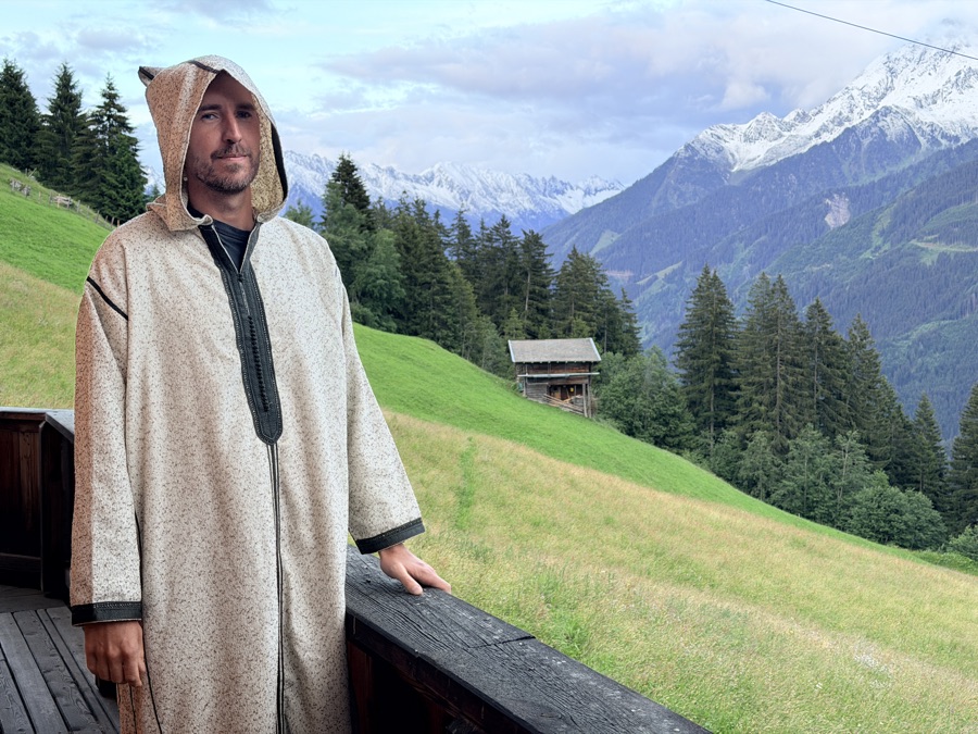 Pawel in a hooded robe with mountains behind him